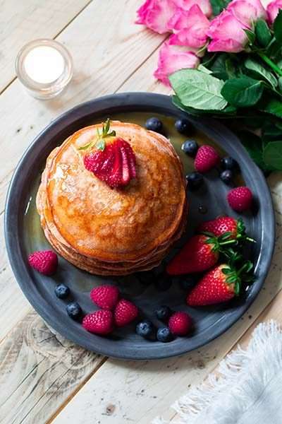 Pink pancakes surrounded by fresh berries.